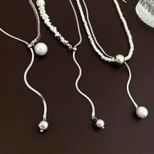 Detail of silver necklaces with faux pearls and Y-shaped adjustable clasp on leather