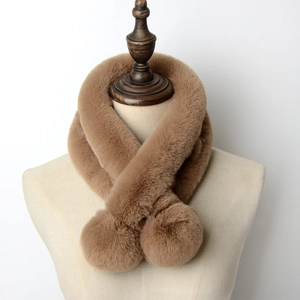 Detail of soft camel faux rabbit fur scarf with decorative pom-poms on a mannequin