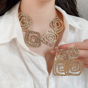 Detail of interlocking hollow square necklace and earrings with hammered gold texture on model