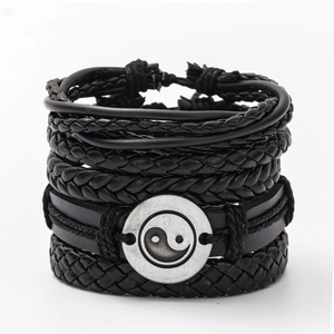 Detail of layered black braided leather bracelet with vintage Tai Chi Yin Yang charm