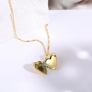 Detail view of an open golden heart locket pendant necklace on a natural stone base