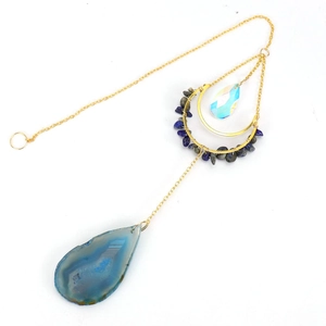 Detail of blue agate slice moon sun catcher with golden chain and crystal charms