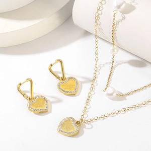 Detail of gold heart pendant necklace and earrings set with Love You engraving and pearls