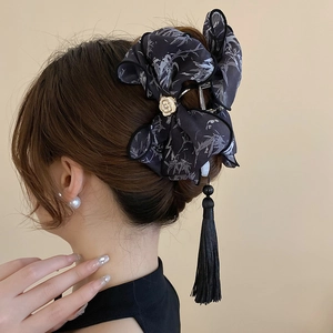 Détail de la pince à cheveux nœud à encre avec long pompon sur coiffure élégante