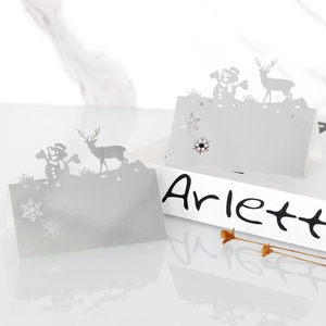 Detail of silver laser-cut Christmas place cards with reindeer and snowman silhouettes