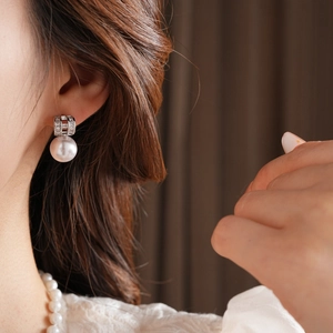 Detailed close-up of a French retro pearl earring with silver geometric accents on a model