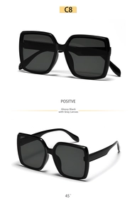 Detail view of oversized square sunglasses in glossy black with full grey lenses