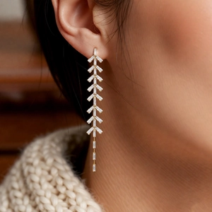 Close-up of gold leaf tassel earrings with white zircon on model in warm natural light