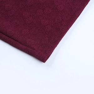 Gros plan détaillé sur la dentelle florale bordeaux et les coutures d'une robe sexy en V