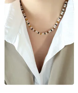 Detail of beaded choker necklace with white jade, tiger eye, and black onyx beads on a model