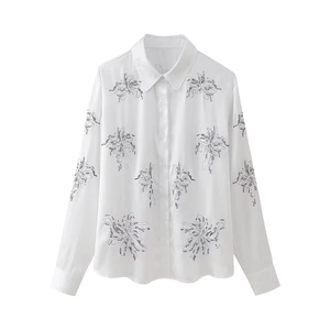 Close-up of intricate floral embroidery and button detail on white cotton shirt