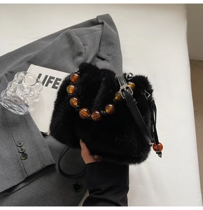 Detail of black faux fur bucket bag featuring amber resin beads and long leather strap