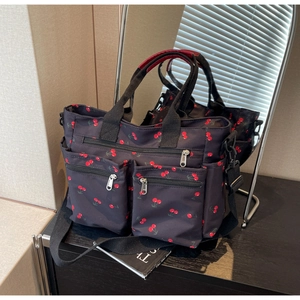 Detail of nylon tote bag with cherry print featuring multiple functional zip pockets