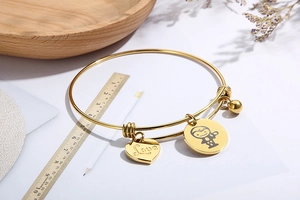 Detail of adjustable gold heart bracelet with Love charm and astronaut pendant with ruler