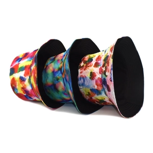 Three tie-dye reversible bucket hats with colorful artistic patterns and black lining