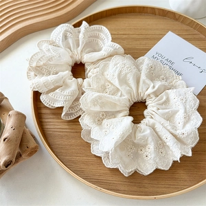 Deux chouchous en dentelle blanc cassé avec broderie florale sur plateau en bois