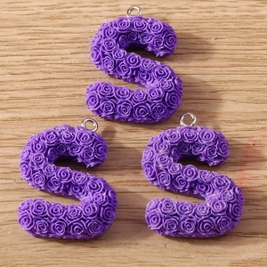 Detail of purple S-shaped resin pendants with embossed rose texture and silver rings