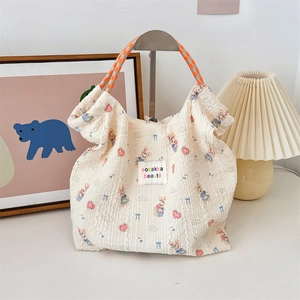 Close-up of cream textured tote bag featuring cute rabbit prints and woven rope handles
