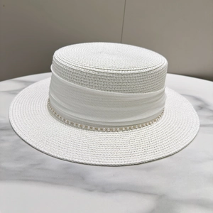 Detail of white straw boater hat with fine weaving, sheer ribbon and pearl chain trim