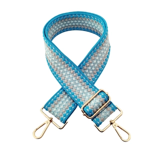 Detail of adjustable blue woven wide shoulder strap with gold metal lobster clasps