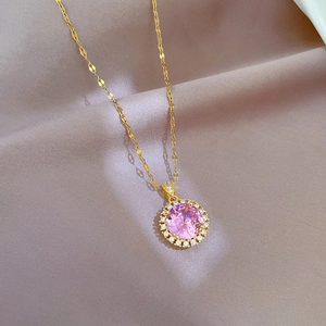 Close-up of gold chain with round pink gemstone pendant and sparkling halo crystals