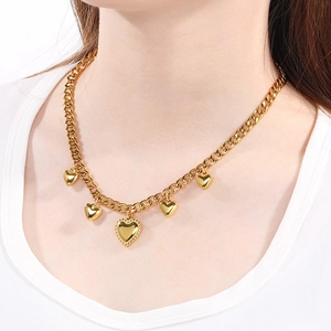 Close-up of gold chunky Cuban chain necklace with five heart charms on a model's neck