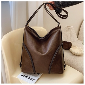 Close-up of a large brown PU leather tote bag with stylish dual diagonal zipper accents