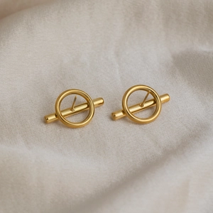 Detail of 18K gold-plated irregular geometric earrings on textured beige fabric