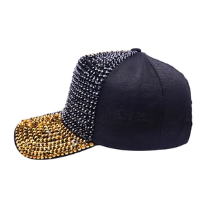 Close-up of black baseball cap featuring gold studs and sparkling rhinestone details