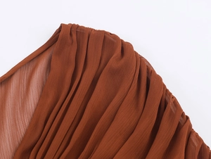 Detailaufnahme der plissierten karamellfarbenen Chiffon-Textur und des feinen Faltenwurfs