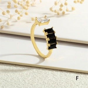 Detailed close-up of a gold open ring featuring white and black rectangular crystals