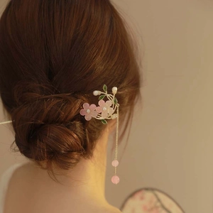 Détail d'un pic à cheveux avec fleurs de muguet roses et glands de perles