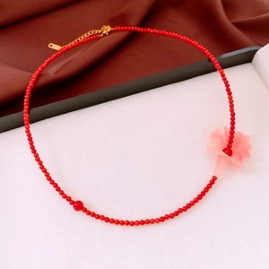 Detail of red beaded necklace with pink flower pendant and gold adjustable clasp