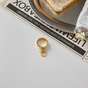 Detail shot of golden OT buckle ring on a metal tray with a creative lifestyle background