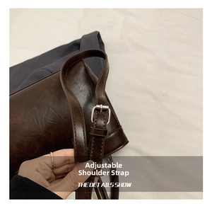 Détail de la bandoulière réglable en cuir marron avec boucle en métal argenté du sac