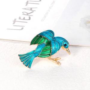 Elegant gold bird brooch with green and blue enamel wings and black gemstone eye detail