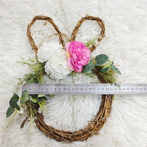 Detail shot of rabbit floral wreath showing 21cm width scale on white plush background
