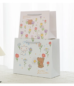 Detail view of pink and blue cartoon bear gift bags with white braided handles