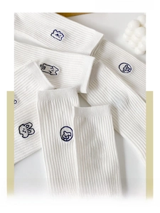Close-up of white cotton socks with cute cartoon animal embroidery and ribbed texture