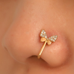 Macro detail of a golden butterfly non-piercing nose clip with shimmering cubic zirconia