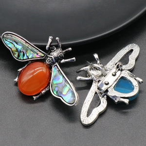 Detailed silver bee brooch featuring orange gemstone and iridescent abalone shell inlay