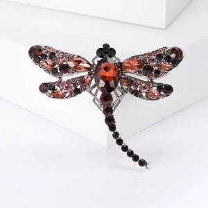 Detailed view of dragonfly brooch with deep red rhinestones and silver metal base