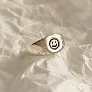 Macro shot of minimalist S925 sterling silver ring with smile face on white paper