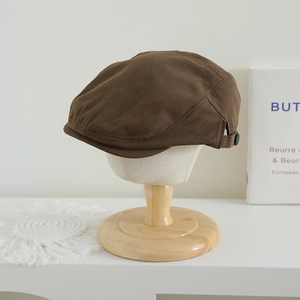 Détail du béret marron foncé pour enfant avec bride latérale et bouton décoratif