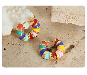 Artistic display of colorful enamel hoop earrings on natural stone and coral backdrop