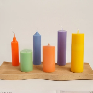 Macro view of six colorful cylinder pillar candles on a wavy wooden tray base