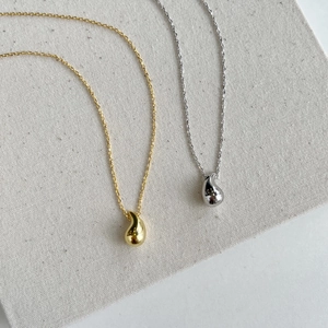 Detailed view of minimalist teardrop pendant necklaces in gold and silver finish