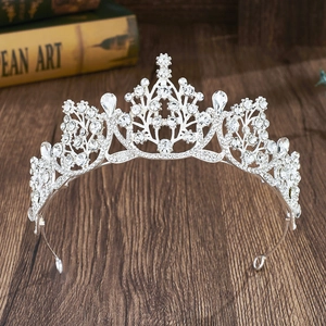 Detailed view of a silver crown with crystals on a dark wood background and books