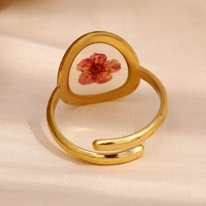Vue macro d'une bague ajustable dorée ornée d'une véritable fleur séchée rouge
