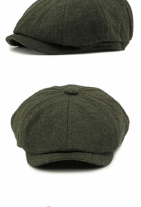 Detail of dark green herringbone newsboy cap featuring classic eight-panel wool blend design